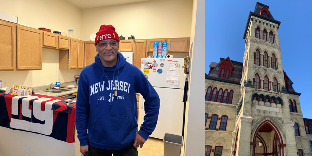 Man in blue hoodie stands in kitchen next to image of building facade