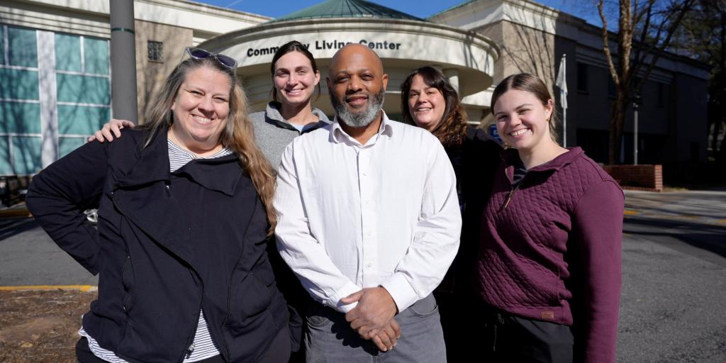 Five people standing outside a building, smiling for the camera.
