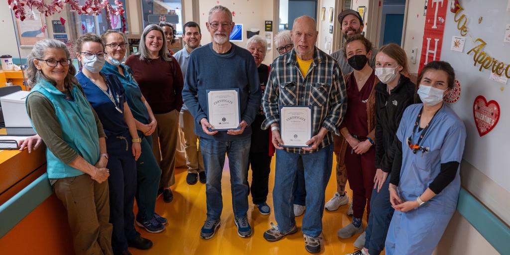 Group of hospital staff and patients holding certificates in a hallway.