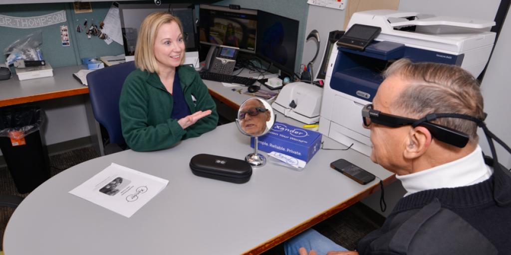 Woman and man in office, discussing with smart glasses on man's face.