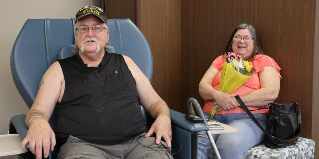 Man in a blue chair and woman with flowers.