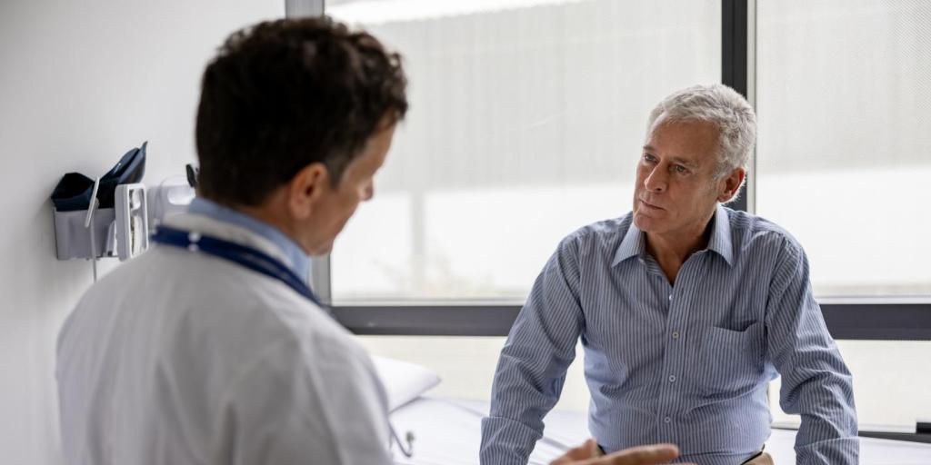 Doctor in white coat consulting older man in clinic.