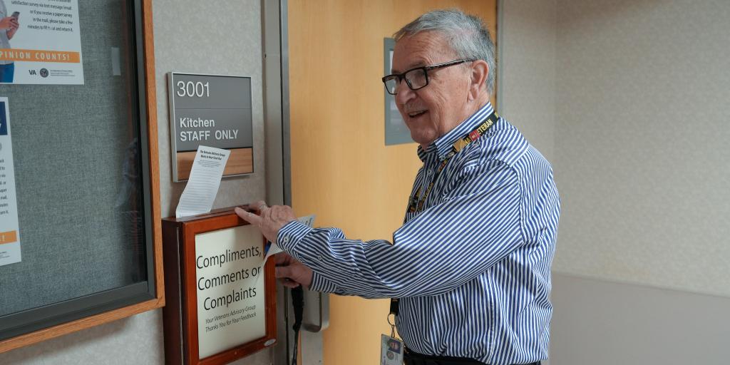 A man in a blue shirt opens a comment box on a wall.