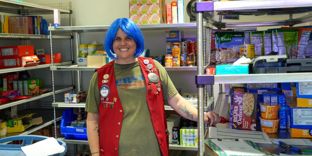 Woman with blue wig and red vest in food bank.