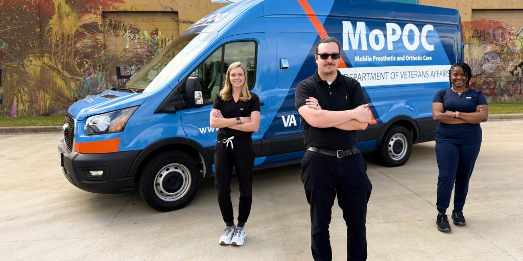 Three people standing next to a blue MoPOC van.