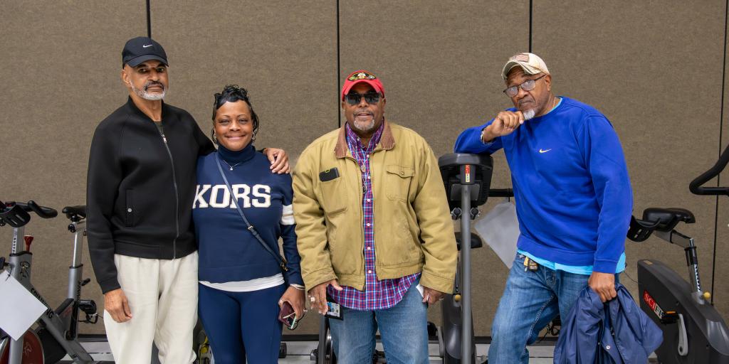 Four people standing together in a gym with exercise bikes.