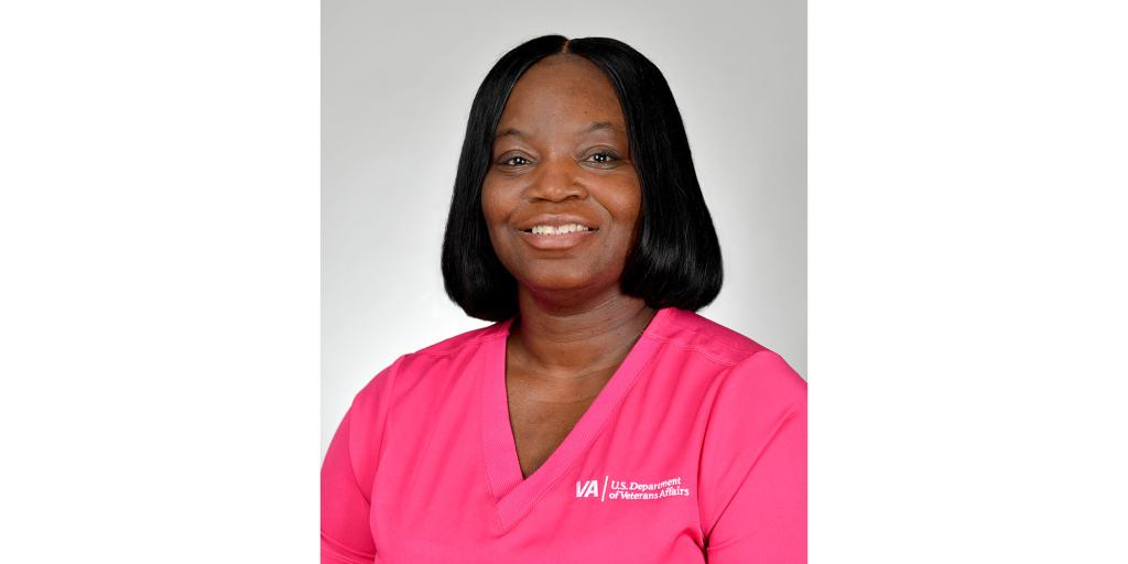 Portrait of a woman in pink scrubs smiling.