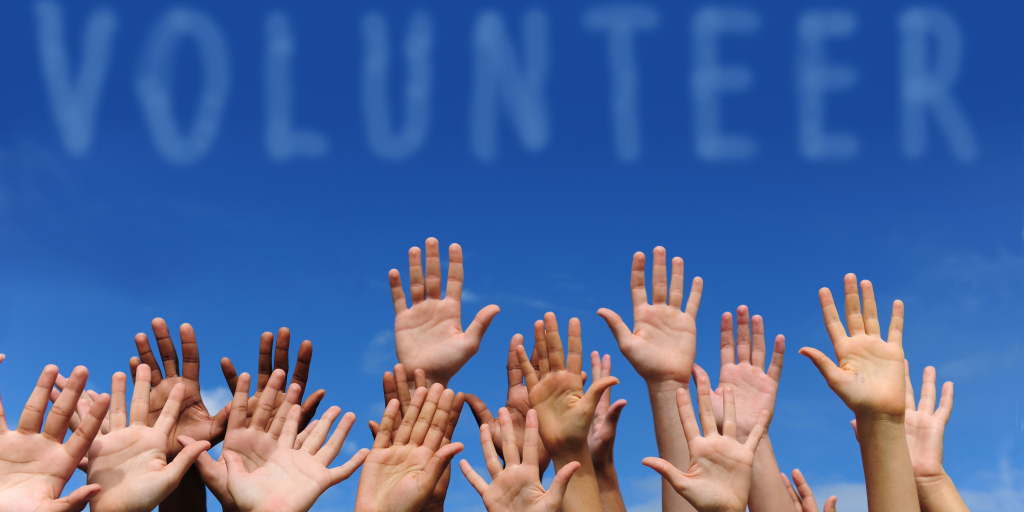 Hands raised against a blue sky with "Volunteer" text.