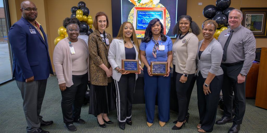 Group of award recipients posing for a photo in an office.