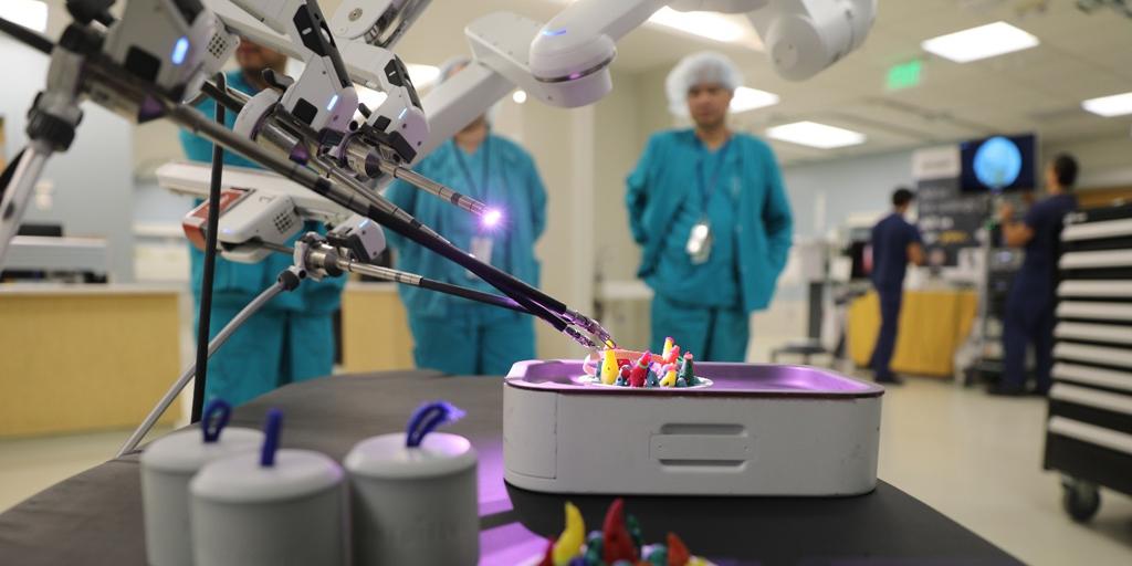 Surgeons in scrubs stand in a hospital room around a machine with colorful objects.