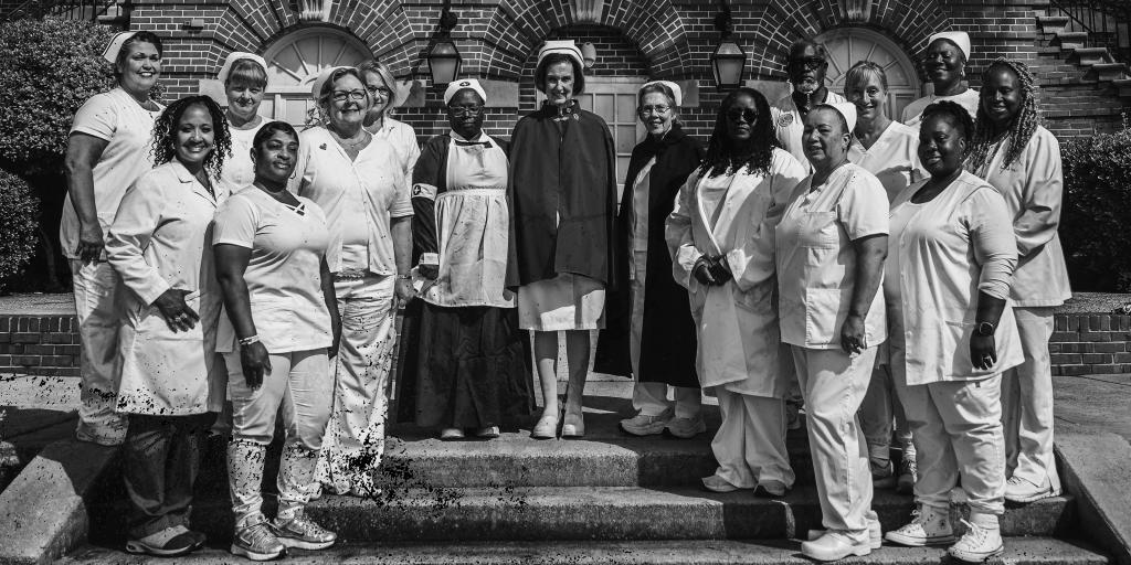 Black and white photograph of a group of nurses on steps outside a building.
