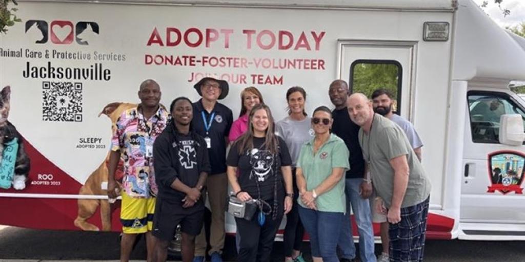 Group photo of volunteers standing in front of an "Adopt Today" van.