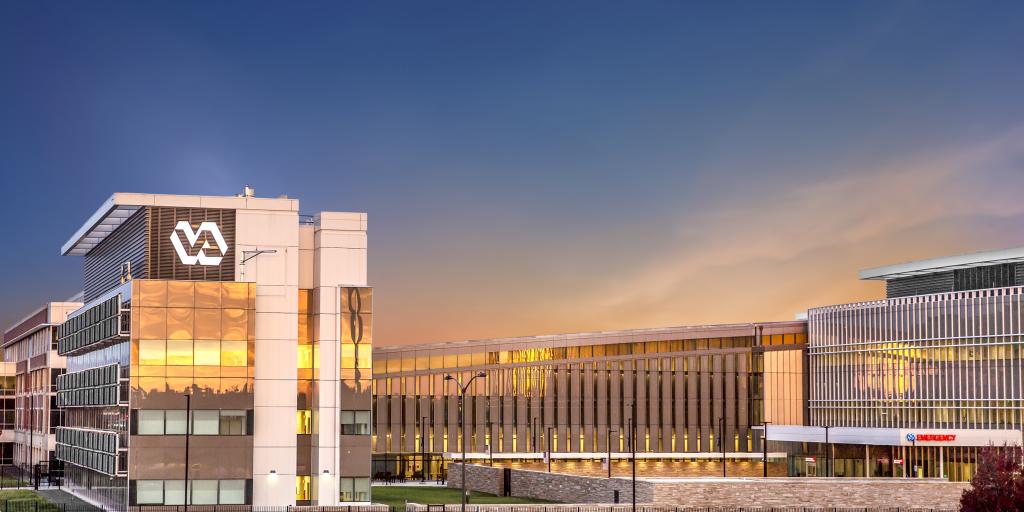 Modern building with VA logo at sunset, featuring glass facades and contemporary design.