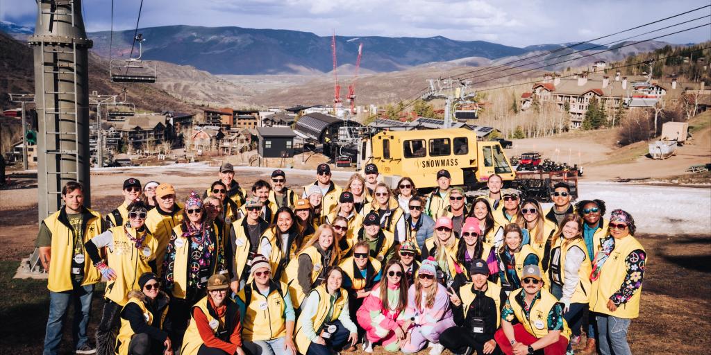 Group photo of people in yellow jackets at ski resort.