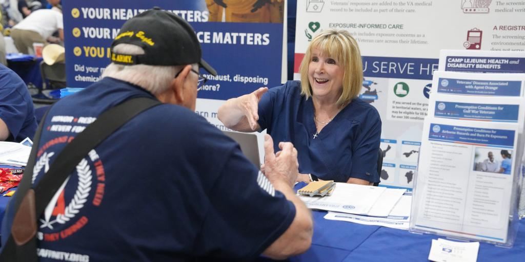 Man in blue shirt talks with smiling woman at a table with blue tablecloth.
