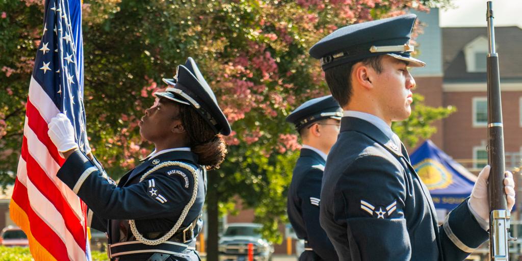 Air Force members in uniform salute the American flag.