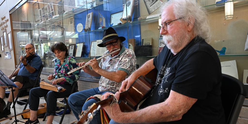 Four musicians playing instruments in a museum setting.