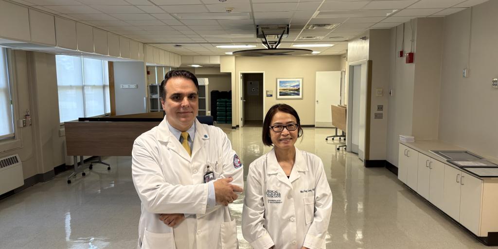 Two doctors in white coats stand in a hospital hallway.