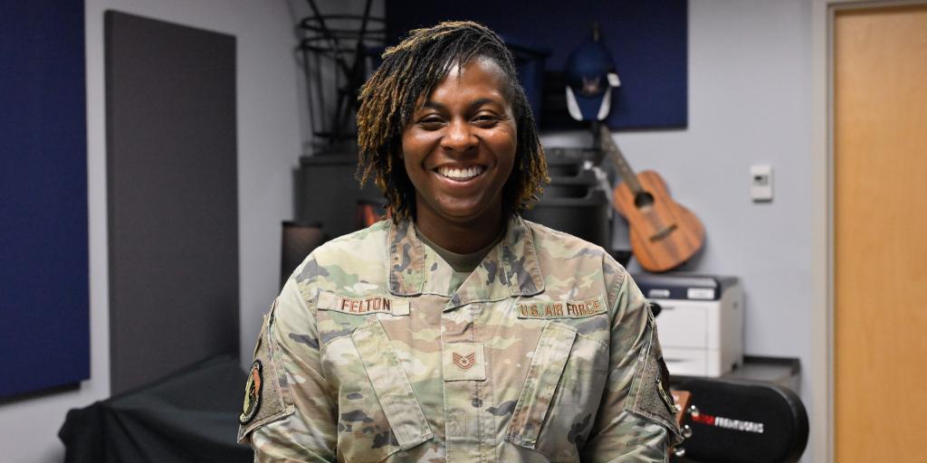 Woman in military uniform smiling in a music room.