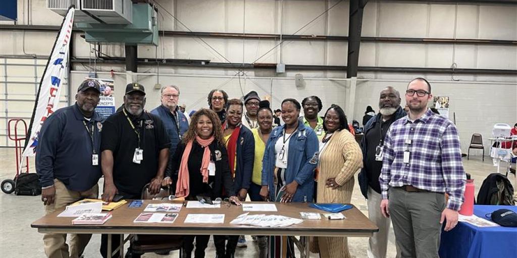 Group of people standing by a table in a hangar.