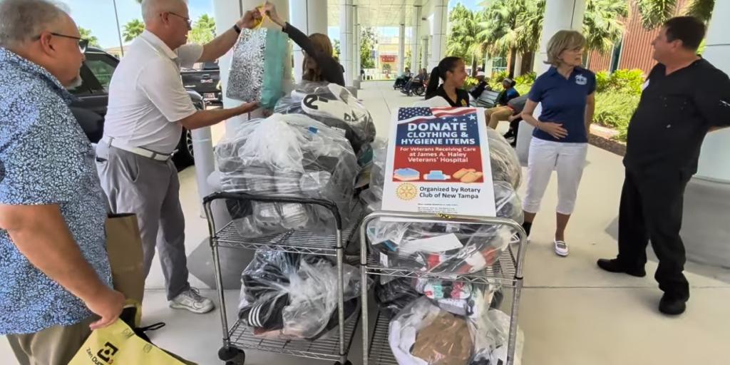 People gather around carts filled with supplies, possibly for a donation event.