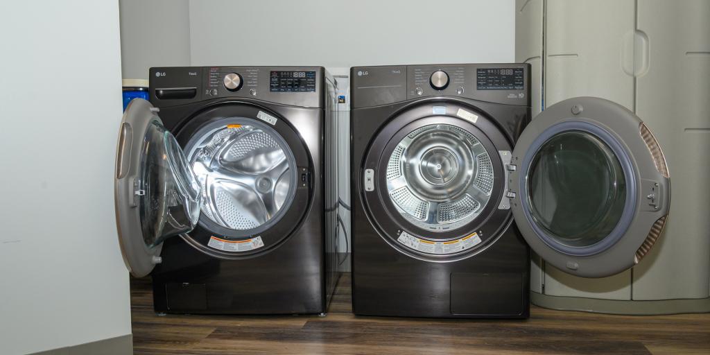 Two black washing machines with doors open on wooden floor.