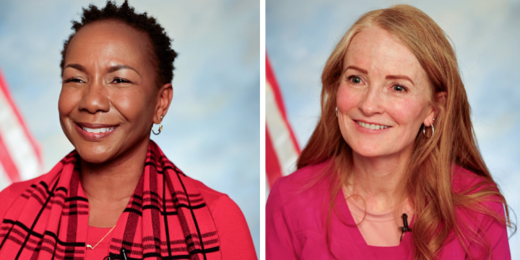 Two smiling women in red and pink shirts with American flags in background.