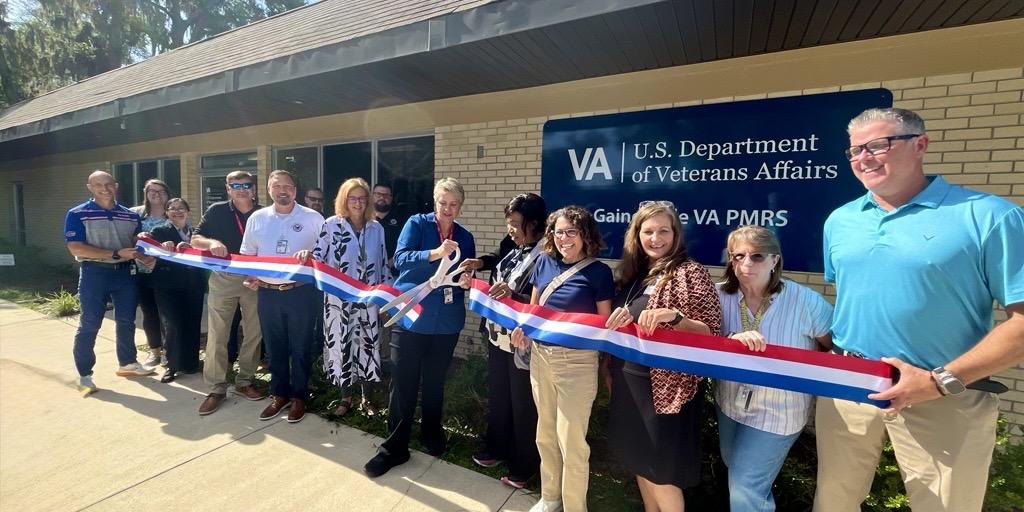 Group of people cutting ribbon in front of U.S. Department of Veterans Affairs building.