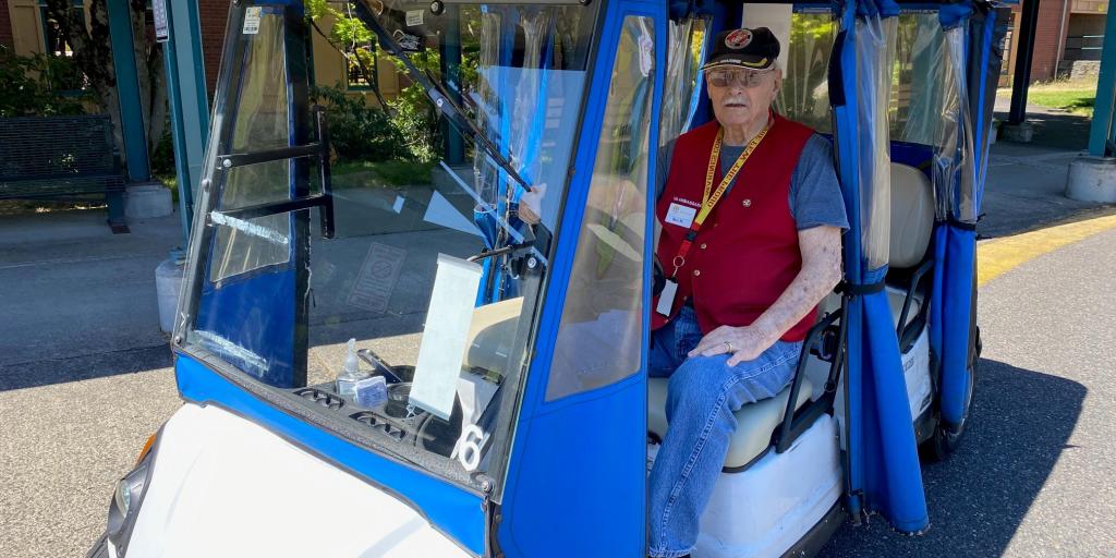 Veteran in a blue and white golf cart on a road.