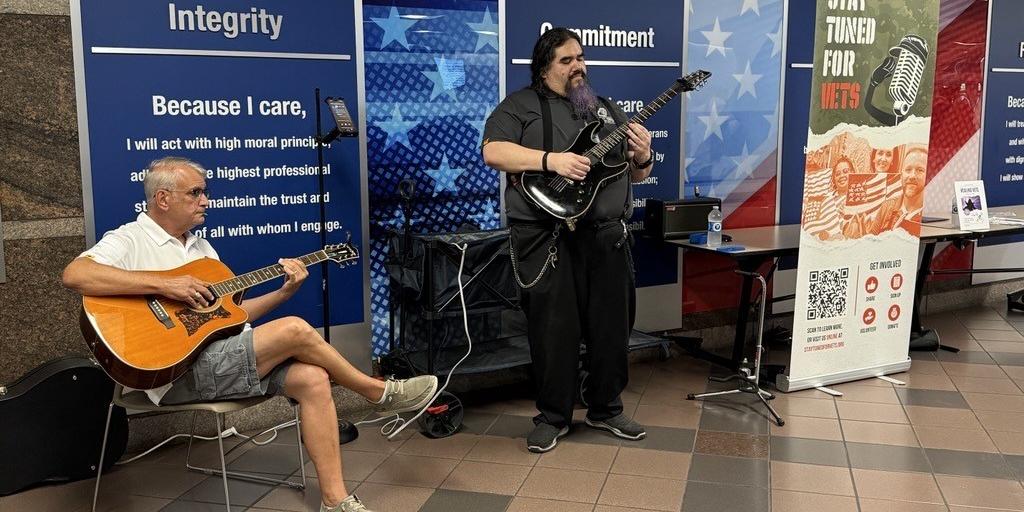 Two men playing guitars at a VA hospital.