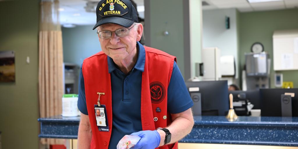 Veteran with red vest and blue gloves at a hospital counter.