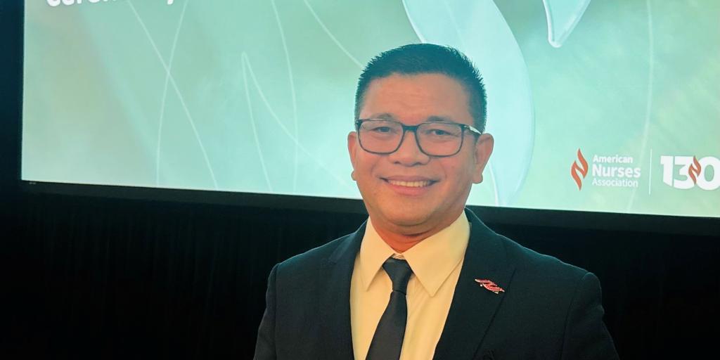 Man in suit holding an award in front of a presentation screen.