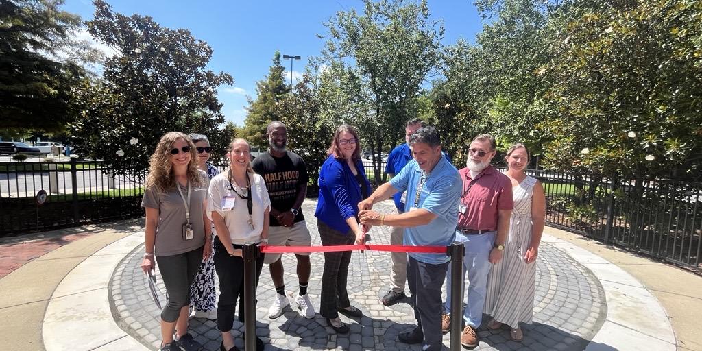 Group of people cutting ribbon at a park.
