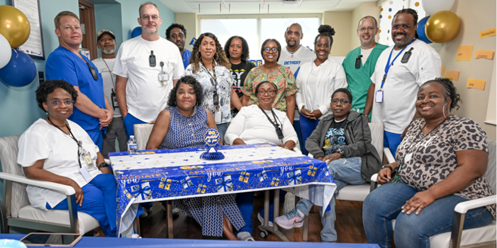 Group of hospital staff celebrating around a table with blue tablecloth.