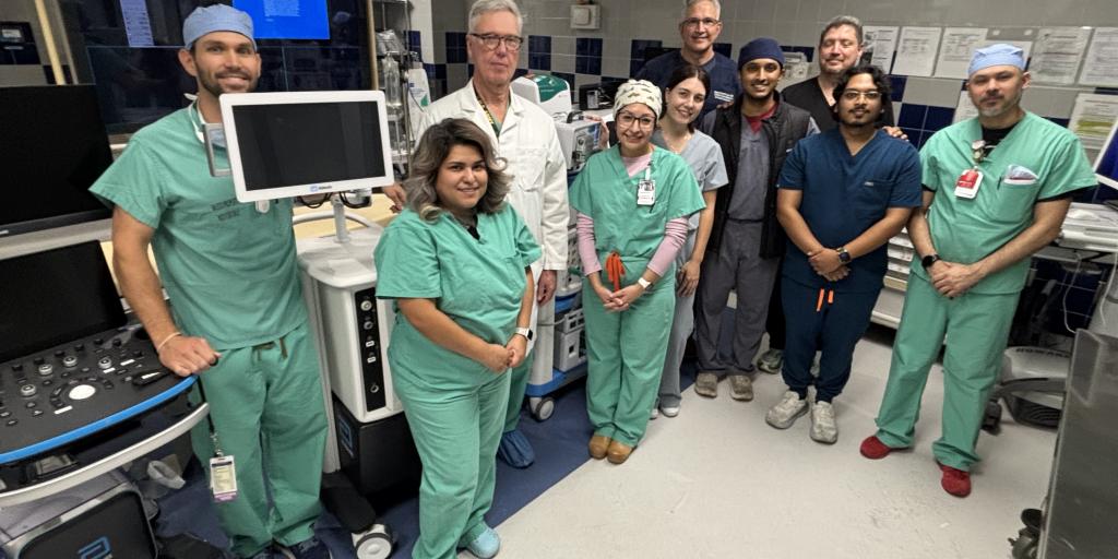 Group of medical professionals in scrubs standing in an operating room.