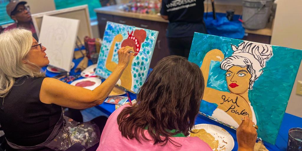 Three women painting at an art workshop, each working on a canvas.