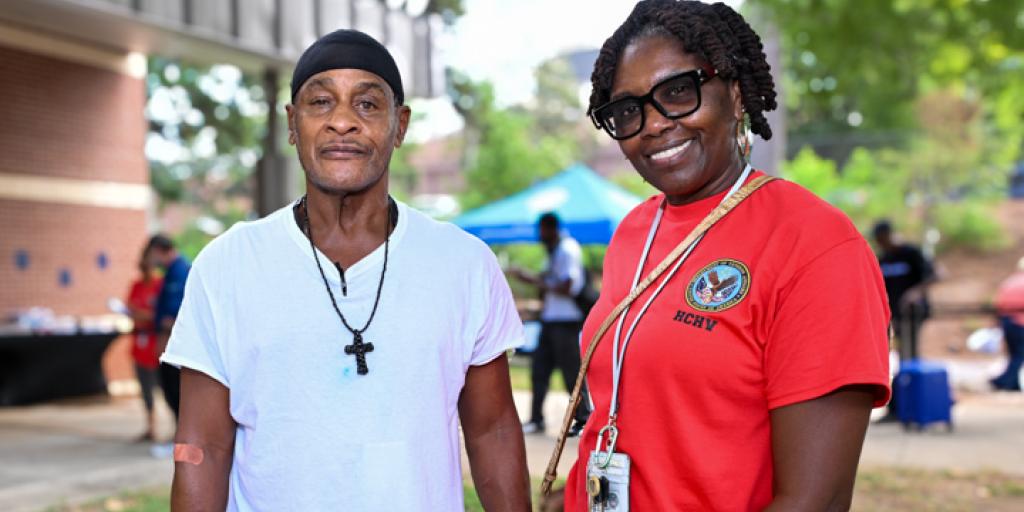Two people stand smiling for a photo in a park.