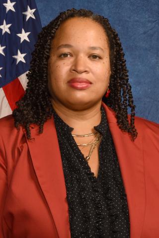 Dr. Lora Cox-Vance in a red suit jacket in front of the American flag