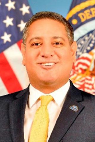Amir Farooqi portrait in front of American and VA flags. 