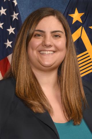 Dr. Jennifer DeFrancesco in her official portrait sitting in front of the American and SES flags