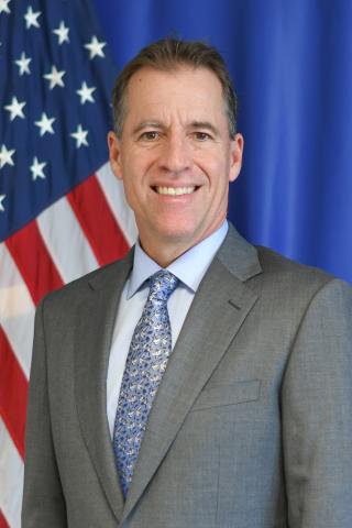 smiling professional male with an American flag in the background