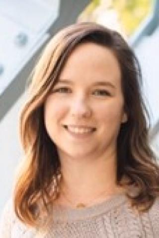 Woman with shoulder length brown hair, beige sweater.