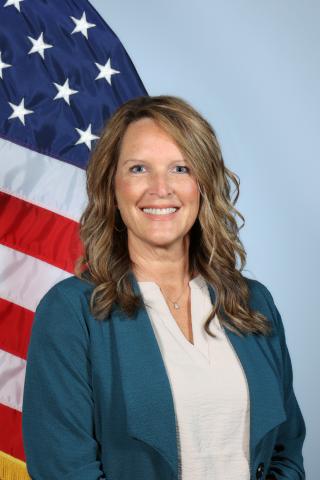Lori Fox poses for a photo in front of the U.S. flag.