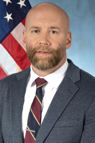 Dr. Daniel McGrath in front of the U.S. Flag