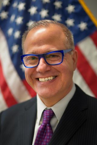 Headshot of Anthony Torggler in front of a US flag