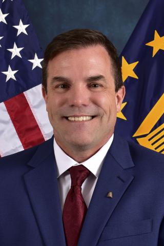 Chad Adams in front of American Flag, smiling