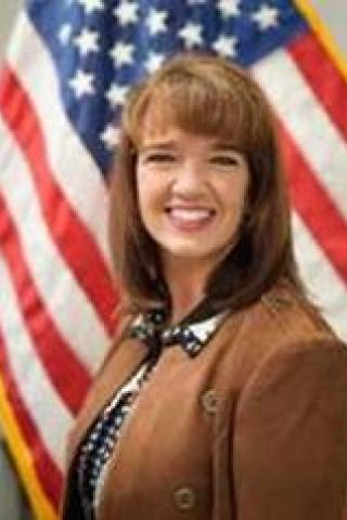 Headshot of Dr. Mary Cavanagh in front of a flag