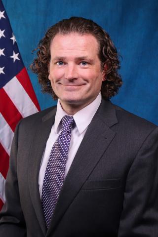 James Paarlberg in front of a blue background and American Flag