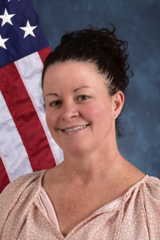 Kimberly in front of American flag and blue background