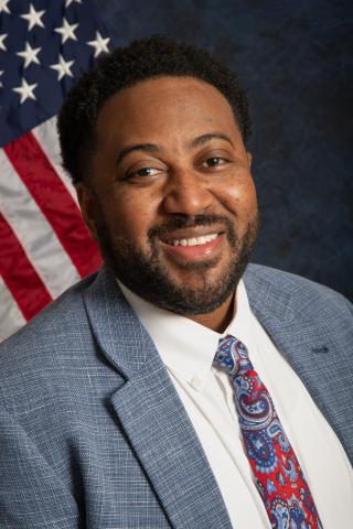 Man in suit with US flag in background.